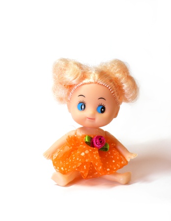 blonde girl baby doll with blue eyes wearing orange dress seated on white backgroundの写真素材