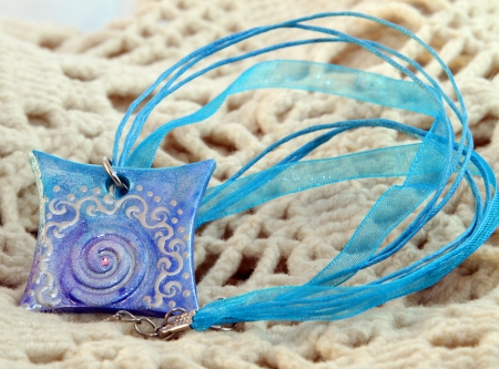 clay handmade blue amulet on a kntited backgroundの写真素材