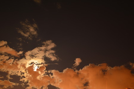 Full moon white clouds covered the part of the moon in the evening summer skyの写真素材