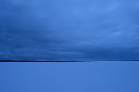 The sky over the lake in winter in dense clouds late in the evening before snow precipitationの写真素材