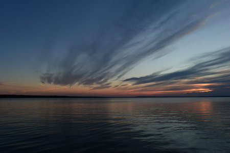 Twilight sky in the glow of sunlight from the clouds reflected on the water surface of the lake
