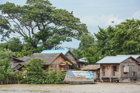 Traditional stilts wooden and bamboo houses and long boats on Ayewadee river in Mandalay, Myanmar Burmaの写真素材
