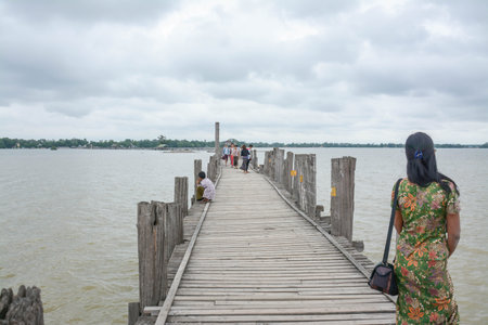 U Bein Bridge, Myanmar-Aug 02th, 2012: Myanmar was walking on U Bein Bridge with his bicycle. U Bein Bridge is the oldest and longest teak wooden bridge in the world.のeditorial素材