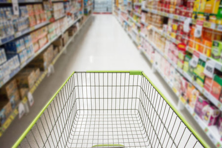Supermarket interior, empty green shopping cart.の写真素材