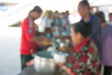 abstract blurred image of puts food offerings in a Buddhist monk's alms bowlの写真素材