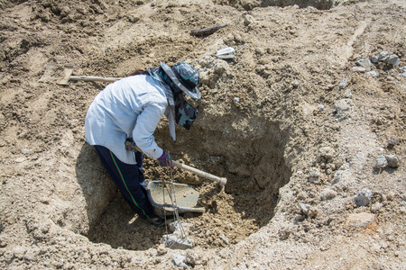 Worker  digging hole with a hoe  at construction siteの写真素材