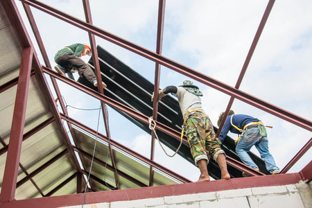 Roofing construction workers  install metal sheet on the roof.の写真素材