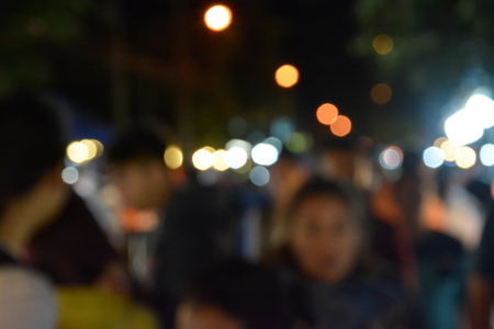 Blurred image of people walking in market at nightの写真素材