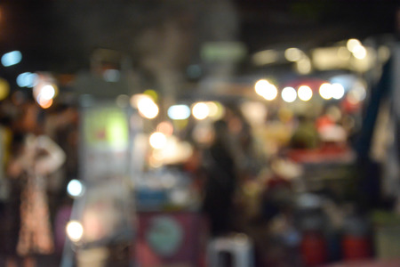 Blurred image of people walking in market at nightの写真素材