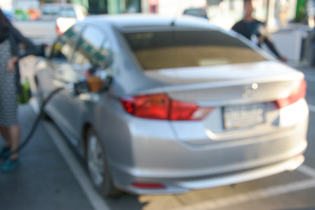 blurred Image holding fuel nozzle and refuel car  in gas stationの写真素材