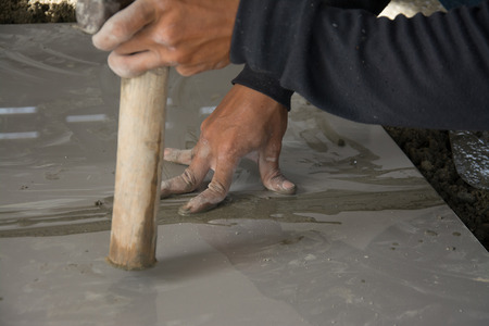 laying ceramic wood tiles on floor, installing tiles  in construction site.の写真素材