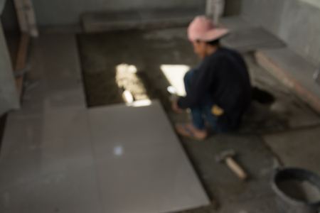 Abstract blurred image of  laying ceramic wood tiles on floor, installing tiles  in construction site.の写真素材