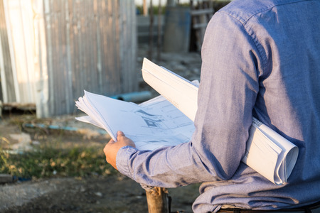 Engineer builder with blueprint at construction siteの写真素材