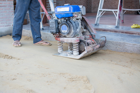 Worker use vibratory plates seals the base sandのeditorial素材