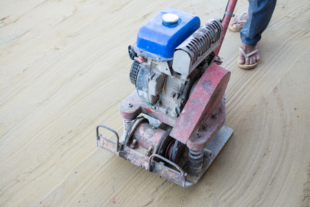 Worker use vibratory plates seals the base sandのeditorial素材