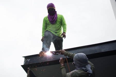 worker  welds the steel structure of the roof at the construction site.の写真素材