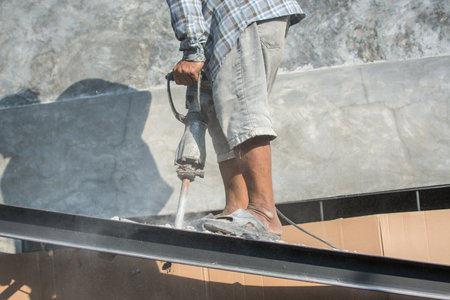 The construction worker is drilling the floor. Construction technicians use electric hammer chisels to destroy the floorの写真素材