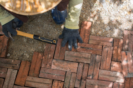 worker laying red brick  pathway around the house