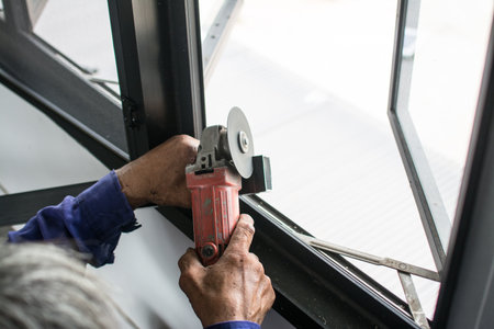 Worker use electric grinder to cut the metal profile of the window.の写真素材
