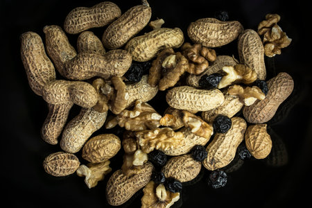 Peanuts,walnuts and dried blue berries on black, Low Key , vignette and  high contrast in studio...