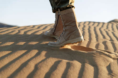 Man in beige clothes and boots sits in the desert. Caucasus, Russiaの写真素材