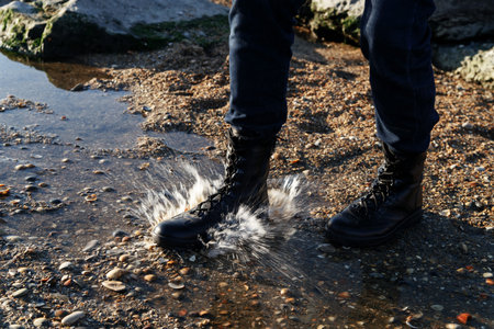 Beige army military boots with laces against the mountains in the beginning of a sunny day....