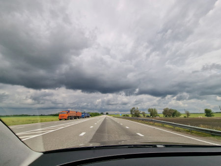 View from the car window on the highway. Car traffic and road markings with rainy sky viewの写真素材