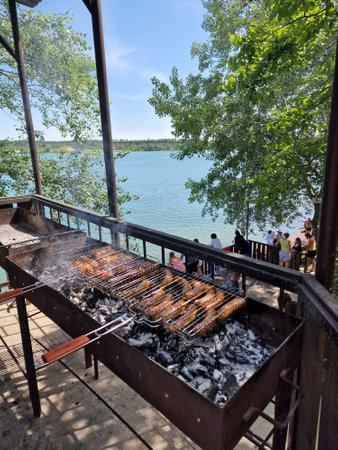 Cooking sausages grilled on the grill in nature near the blue lake in summerの写真素材