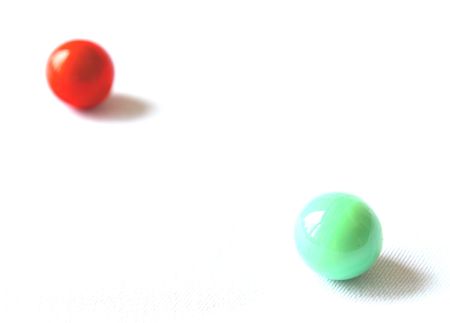 Red and green bead balancing on a white background.の写真素材