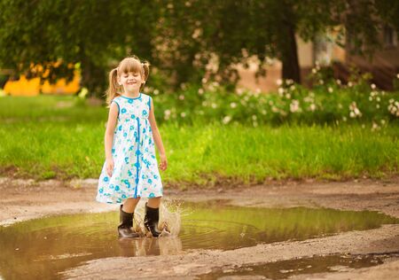 Little kid girl runs through a puddle. summer outdoorの写真素材