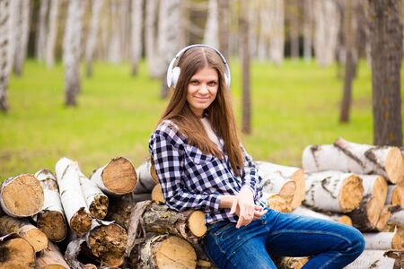 Pretty girl listening music with her headphones in summer city parkの写真素材