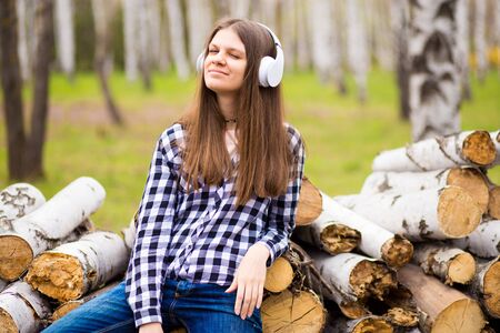 Pretty girl listening music with her headphones in summer city parkの写真素材