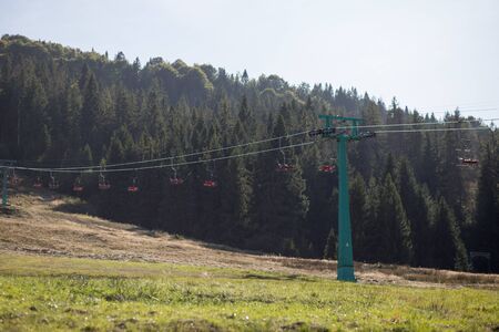 Side view of red chairlift ride to mountains with beautiful nature background. Ukrainian Carpathiansの写真素材