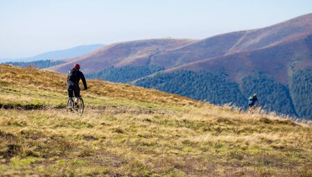 Young bright sport man ride on bike by top of mountainsの写真素材