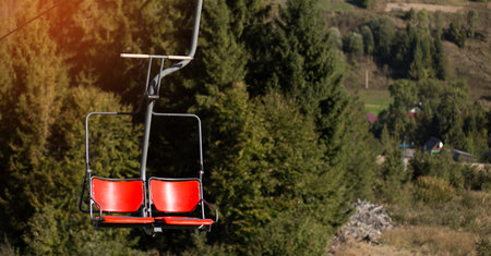 Close up of red chairlift going over trees in summer on Mountain. Carpathian national park