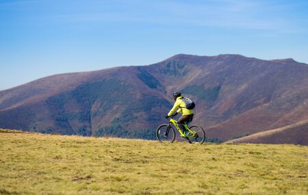 Pylypets, Ukraine - 15 September, 2019: Young bright sport man ride on bike by top of mountainsのeditorial素材