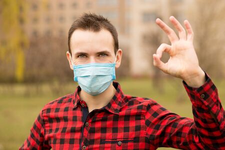 Serenity man wearing protective mask show gesture ok using hand up walk outdoorの写真素材