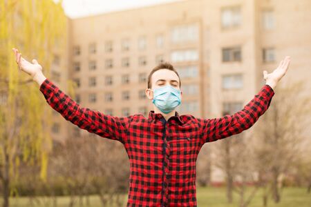 Serenity man wearing medical mask with hands up outdoor in city and praying to thank god for life. Keep calmの写真素材