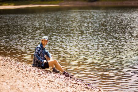 Tourist young man walking on the forest lake beach in summer. Vacation conceptの写真素材