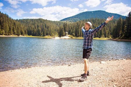 Free man with open arms near mountains lake. success. Travel and Freedom concept. Good life.の写真素材