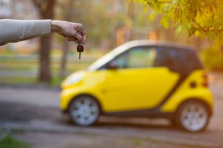 Businessman holding car key with yellow car on backgroundの写真素材