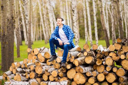 Happy man wearing headphones listening to music checking smart phone walking in city parkの写真素材
