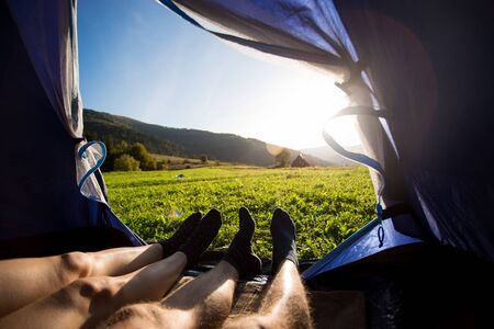Two people lying in tent, view from inside. Couple camping with beautiful view of mountains sunsetの写真素材
