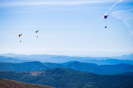 Paragliding group in air sport on top of a mountain. The whole world is in sight. Like a bird, out of gravityの写真素材