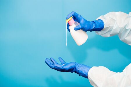 Person hand in blue glove hold soap bottle isolated on blue background. Hands hygiene virus spreading pandemic preventionの写真素材
