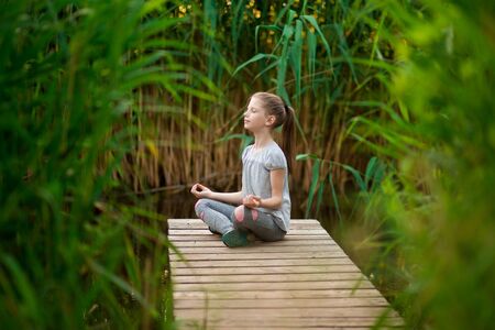 Girl meditating at sunrise on the beach near riverの写真素材