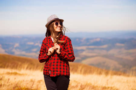 Girl in sunglasses with hat walk with happiness on top of mountain range in autumn. Feeling freedomの写真素材