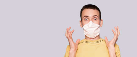 Banner view of scared man in fear with hans up in protective medical mask against viruses and infections isolated on white background. Coronavirus 2019-ncov covid-19 concept.の写真素材