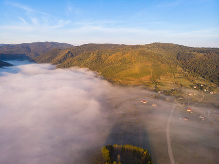 aerial drone view of autumn sunrise on mountain village over clouds
