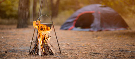 Hiking pot in bonfire with blue tent in autumn forest travelingの写真素材